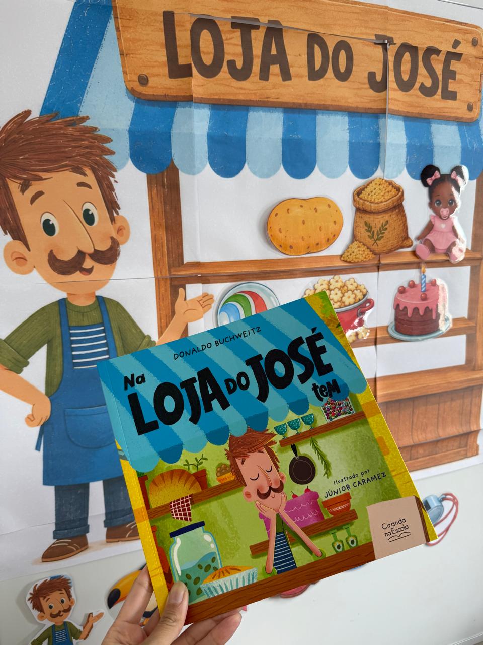 Foto real do livro e do mural da lojinha montado na parede